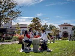 three students seated at outdoor table on Montclair campus